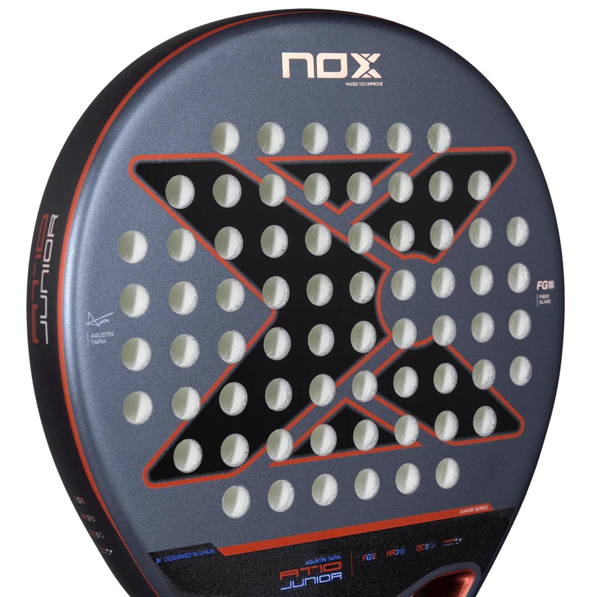 Close-up of the NOX AT10 Genius Junior By Augustin Tapia 2025 padel racket, featuring a bold black "X," circular perforations, and red details on a matte gray surface. "Junior" and "FG8" are shown on the side—ideal for young players.