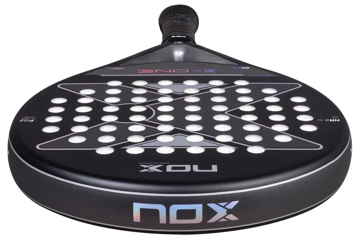 The NOX X-One Advance Series Padel Racket in black features a white hole grid, large X pattern, and an HR3 rubber core for enhanced performance, shown from the front with the handle at the top. Brand: NOX.