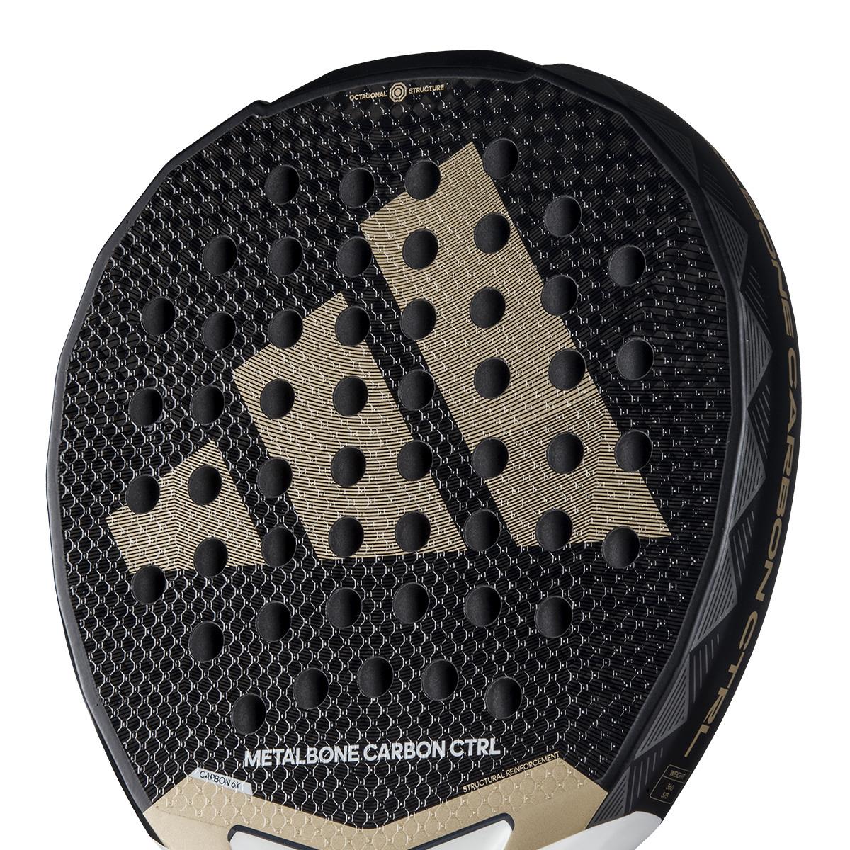 The adidas Metalbone Carbon CTRL 3.4 Padel Racket in black and gold features a sleek pattern with circular indentations, ideal for advanced players. "Metalbone Carbon CTRL" is elegantly printed on the lower part of the racket.