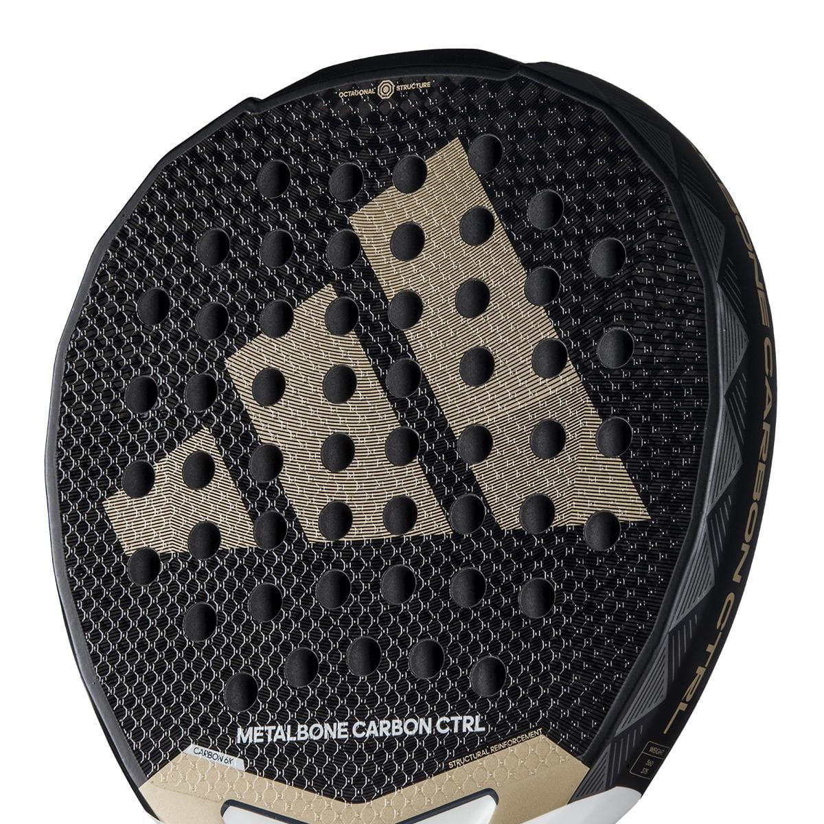 The adidas Metalbone Carbon CTRL 3.4 Padel Racket in black and gold features a sleek pattern with circular indentations, ideal for advanced players. "Metalbone Carbon CTRL" is elegantly printed on the lower part of the racket.