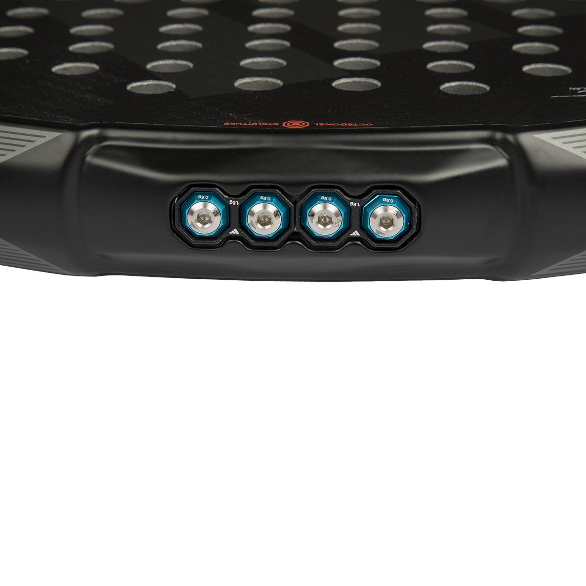 Close-up of the ADIDAS Metalbone 3.4 padel racket in black and white, featuring a textured surface and four hexagonal weight adjustments with blue rims near the base, ideal for advanced players wanting customized weight distribution.