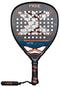 The NOX AT10 Luxury Genius Attack 18K Alum By Agustin Tapia 2025 padel racket features a black design with orange accents, a textured surface with holes, an "X" center motif, and a black and orange grip with a matching wrist strap.