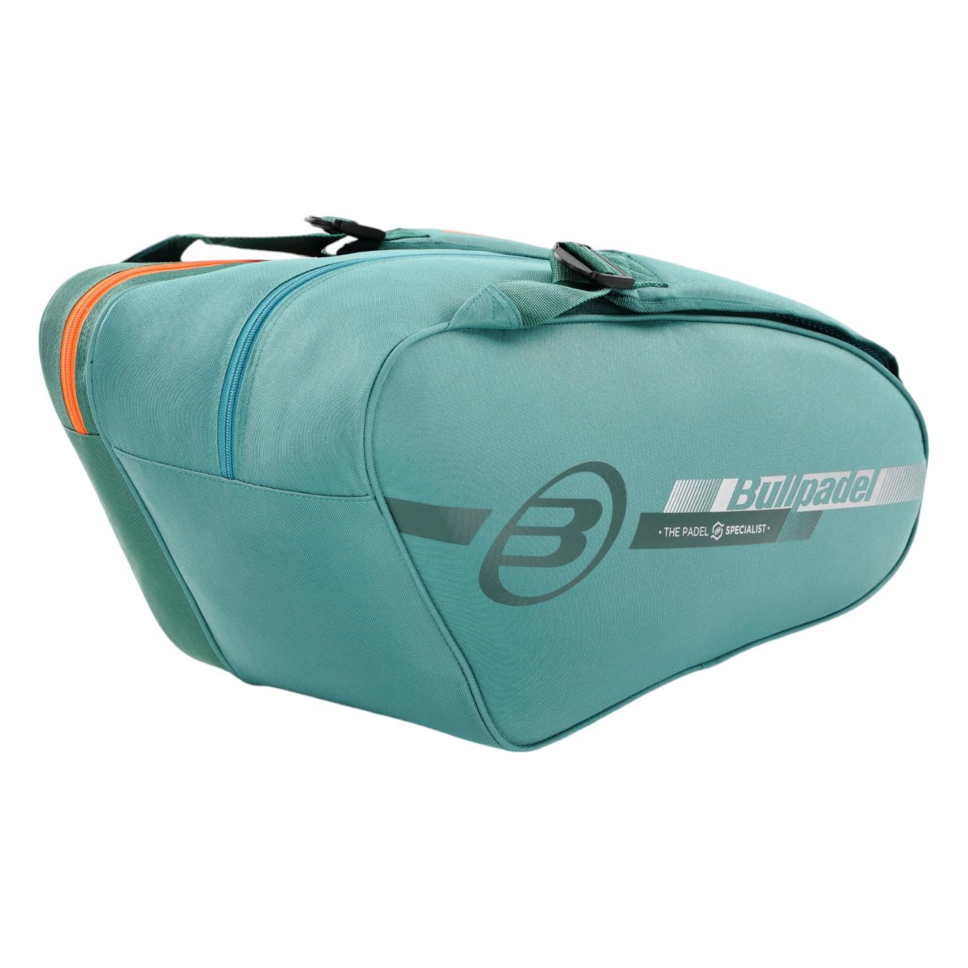 The Bullpadel Tour 25 Padel Racket Bag in teal boasts a sleek design with two large compartments featuring orange and teal zippers. Lightweight and spacious, it has a black handle and displays the "B" logo and "Bullpadel" branding on the side, along with "The Padel Specialist.