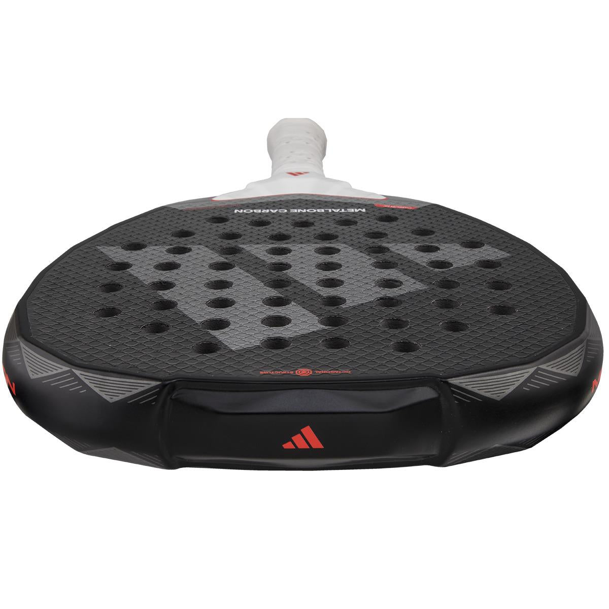 Close-up of the adidas Metalbone Carbon 3.4 Padel Racket in black/white, showcasing its textured surface with holes. Designed for advanced players, it has a white grip handle and features red accents and a logo on the edge.