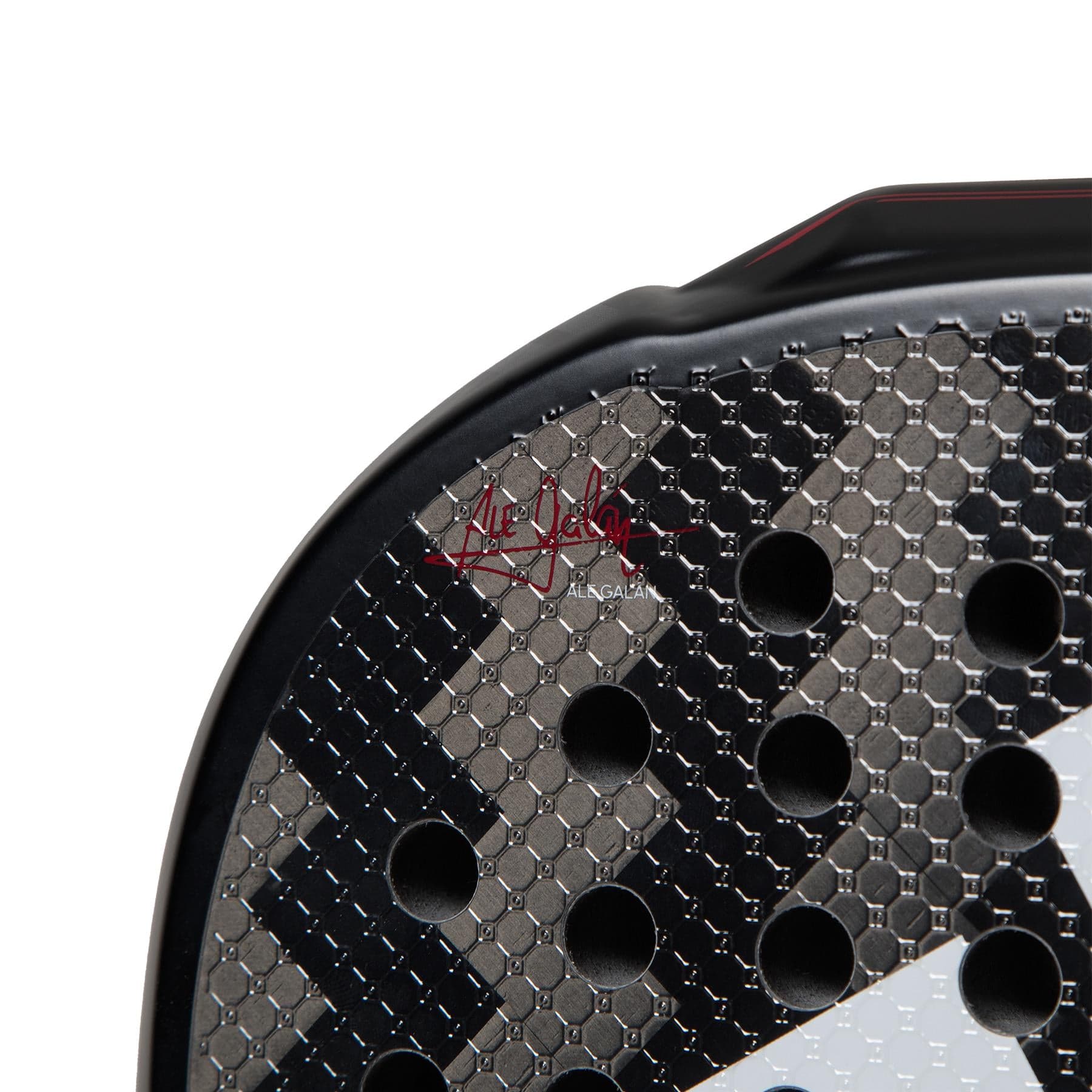 A close-up of the sleek, modern ADIDAS Metalbone 3.3 padel racket showcases its black hexagonal texture with circular holes. The top left corner features a partially visible red "Ane..." signature, catering to power and advanced players seeking top performance.