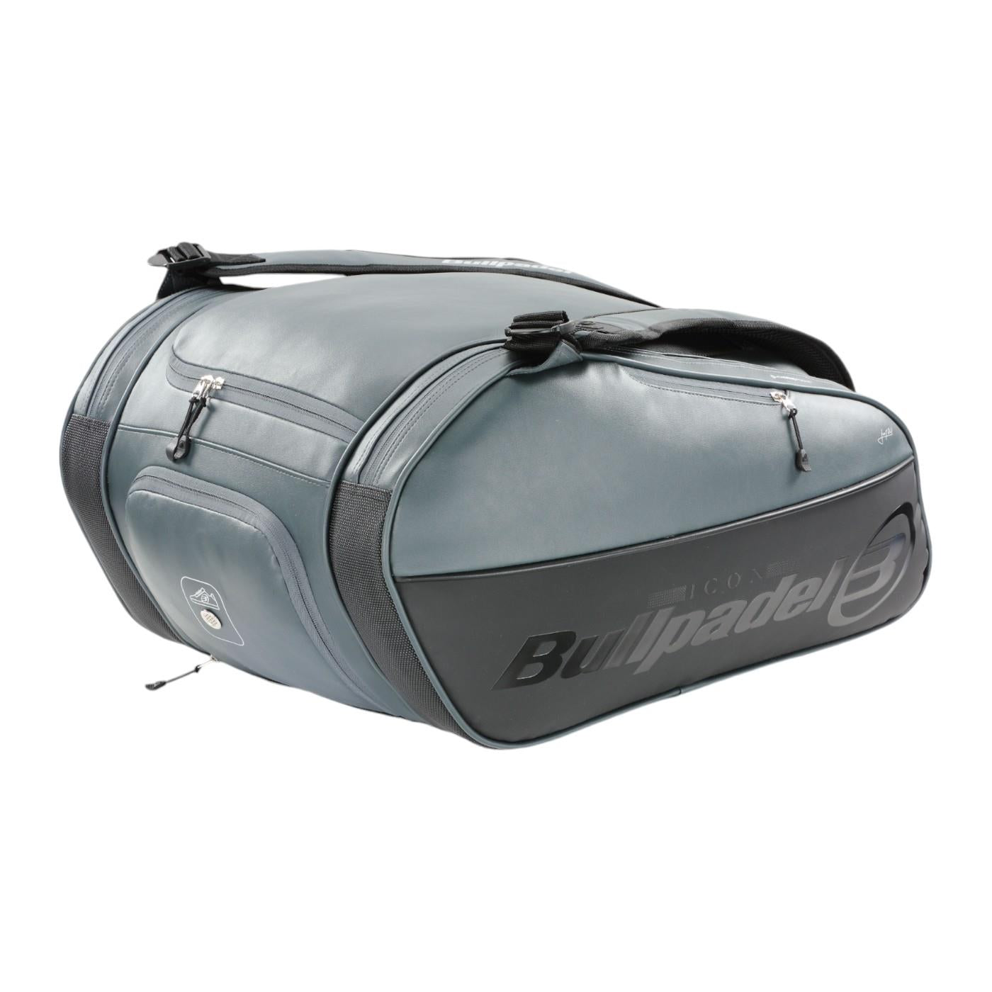 The Bullpadel Icon 25 Padel Racket Bag - Graffiti is a large, sporty bag in dark gray with black accents and silver zippers. It features Bullpadel's name and Juan Martín Díaz's signature on the side, plus a shoulder strap and side handles for easy carrying.