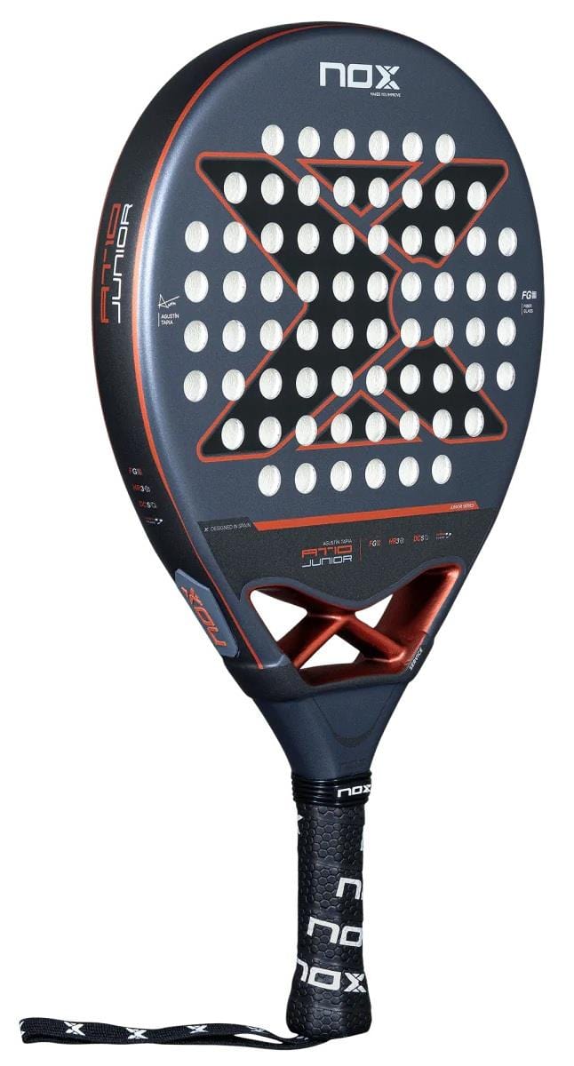 The NOX AT10 Genius Junior by Augustin Tapia 2025 is a black padel racket with a red and white “X” design, carbon frame, round holes, “AT10 Junior” branding, black NOX grip, and wrist strap—ideal for young players’ development.