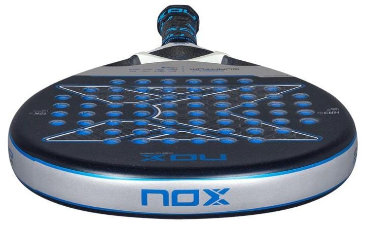 A close-up of the NOX Luxury Quantum 12K Cobalt 2025 Padel Racket in black and blue, showing its perforated face, blue accents, and "NOX" branding—crafted with 12K carbon fibre for premium performance.