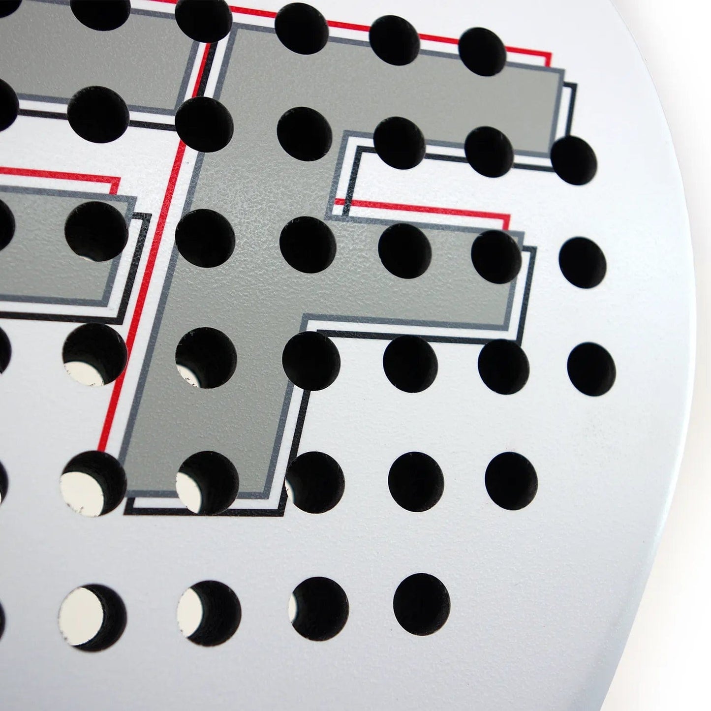 Close-up of a white circular object with a perforated pattern, similar to the design on the Karakal FF 365 Padel Racket by Karakal. The surface displays a large gray letter "F" outlined in red and black.