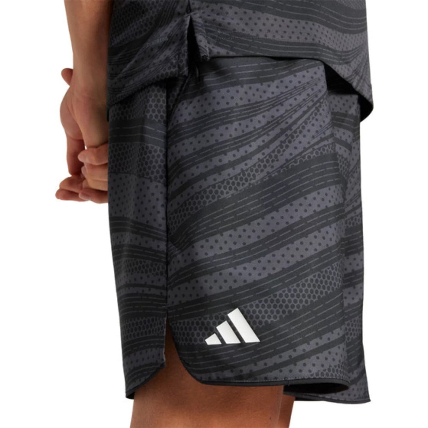 Wearing the ADIDAS Club Graphic Mens Padel Shorts in black with textured stripes, made from recycled materials using AEROREADY, a person stands with hands clasped behind their back.