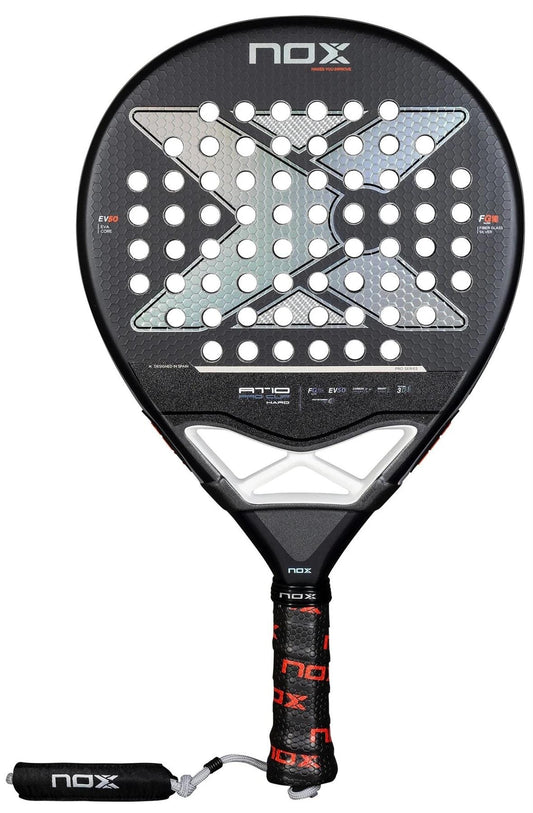 The NOX AT10 Pro Cup HARD By Agustin Tapia 2025 Padel Racket features a perforated surface, large "X" design, black grip with red and white NOX branding, attached wrist strap, and Smartstrap® system for enhanced safety.