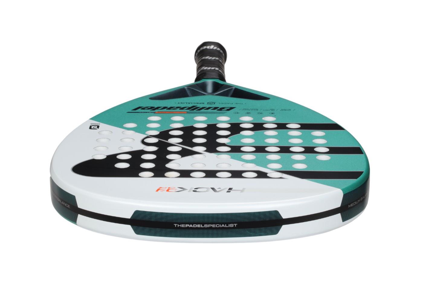 The Bullpadel Hack Junior 25 Padel Racket in teal and white features a diamond head shape perfect for advanced junior players. Its geometric patterns and holes, combined with a black handle, enhance style while the Carbon Tube frame boosts durability and performance.