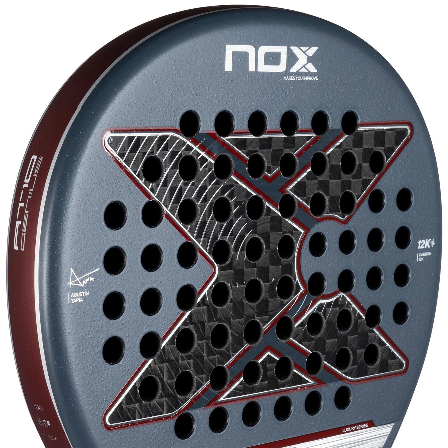 Close-up of the NOX AT10 Luxury Genius 12K By Agustin Tapia 2025 Padel Racket, showing a bold “X” design, multiple round holes, carbon fibre for Exclusive Spin, and a dark gray/red look with NOX branding at the top.