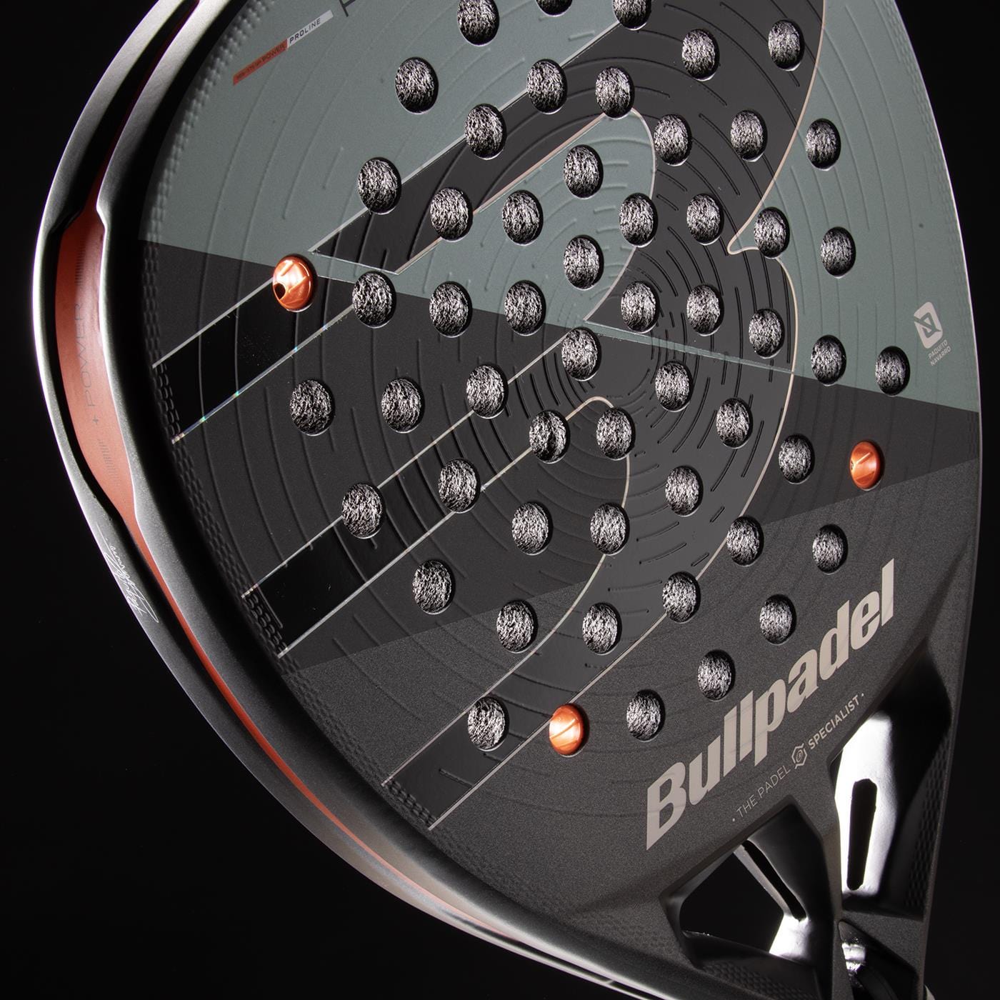 Close-up of the Bullpadel HACK 04 Comfort 2026 Padel Racket in grey, showcasing a textured surface with circular perforations and orange accents. The Bullpadel logo appears on the lower right side, reflecting its dynamic power and modern design.