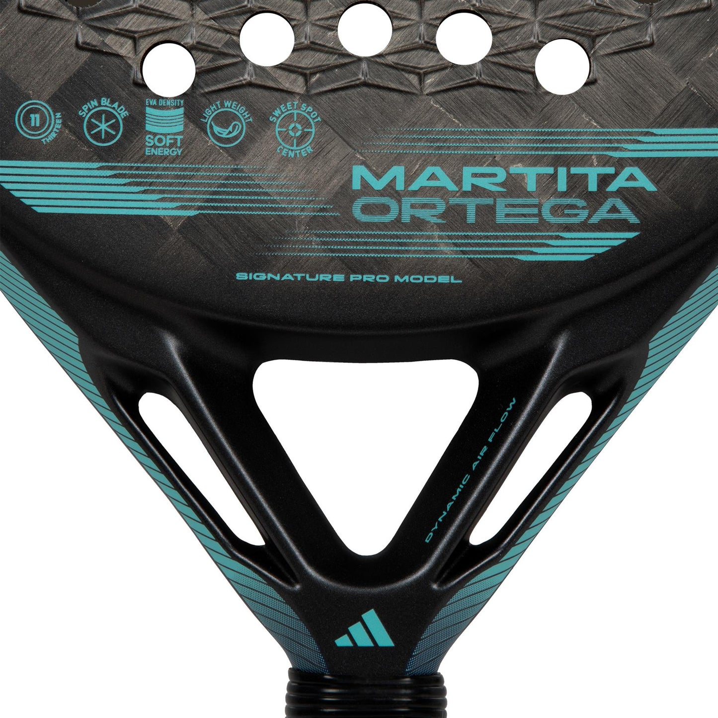 A detailed view of the ADIDAS Cross It Light Padel Racket - Black, highlighting "Martita Ortega" printed on it with a distinctive pattern of holes and branding elements such as "Signature Pro Model." The paddle, adorned with turquoise accents, features advanced Carbon Aluminized 24K technology for optimal lightweight control.