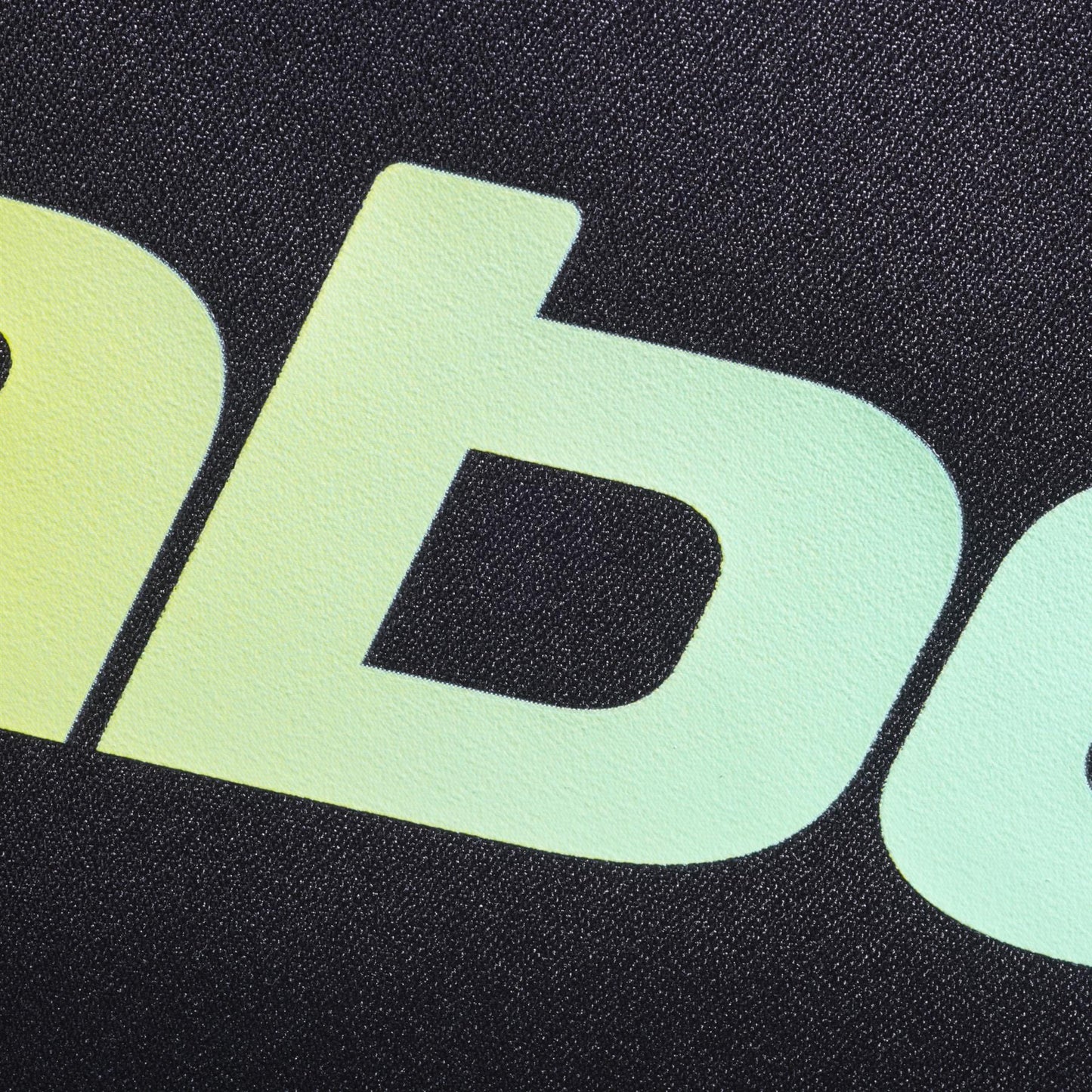 Close-up of lowercase yellow-green gradient letters "ab" on textured black evokes the modern, bold style of the Babolat Court S Padel Racket Bag - Black / Multi by Babolat, made from recycled polyester.