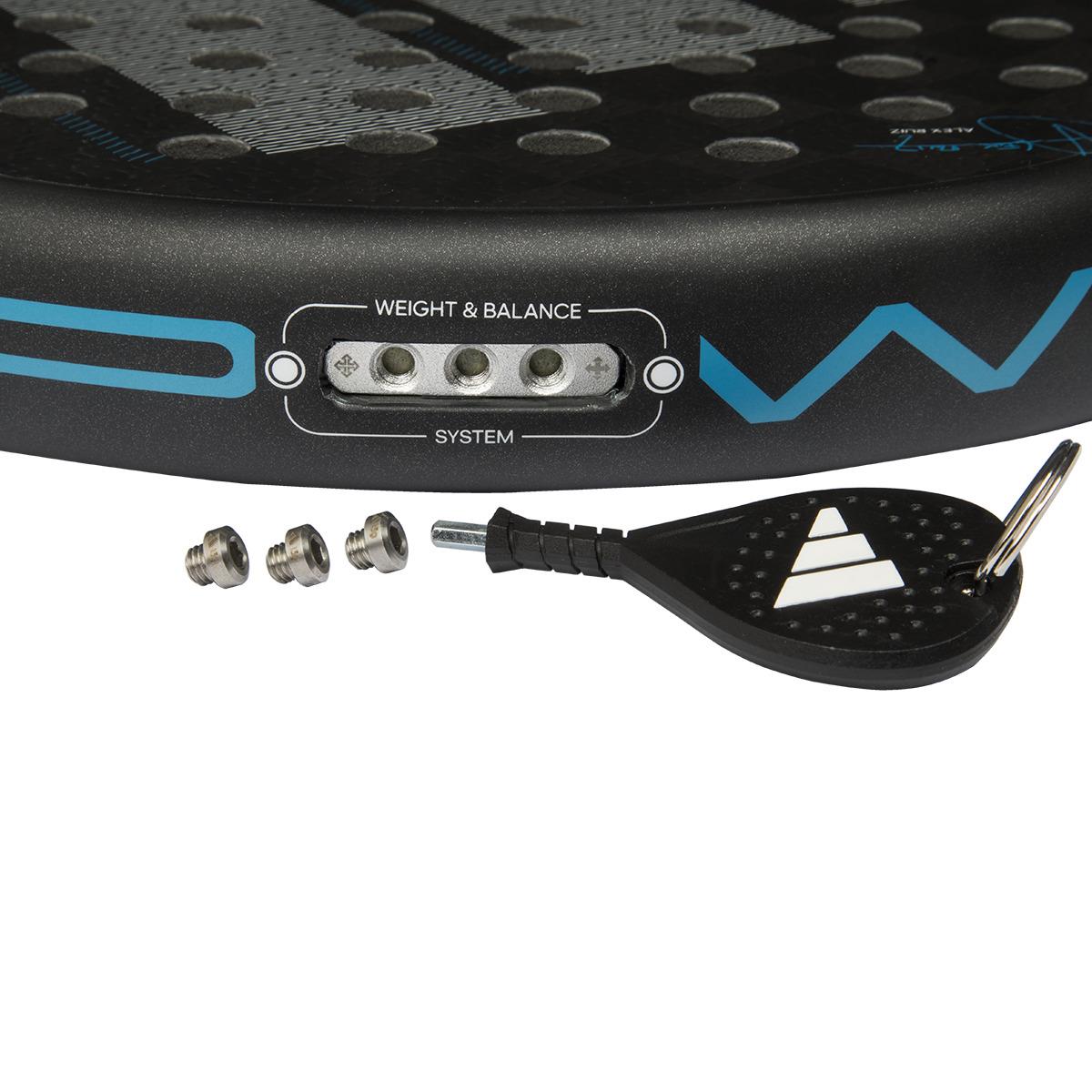 Close-up of an ADIDAS Adipower Multiweight CTRL 3.4 Padel Racket in black and blue, showcasing the "Weight & Balance" system. Three metal weights and a black tool with a keyring are nearby, akin to Álex Ruiz's preferred precision equipment.