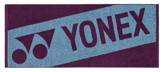 The Yonex AC1113EX Padel Sports Towel - Bordeaux is a rectangular cotton towel with the Yonex logo and name in bold letters on a contrasting two-tone blue and dark purple background, creating an eye-catching design.