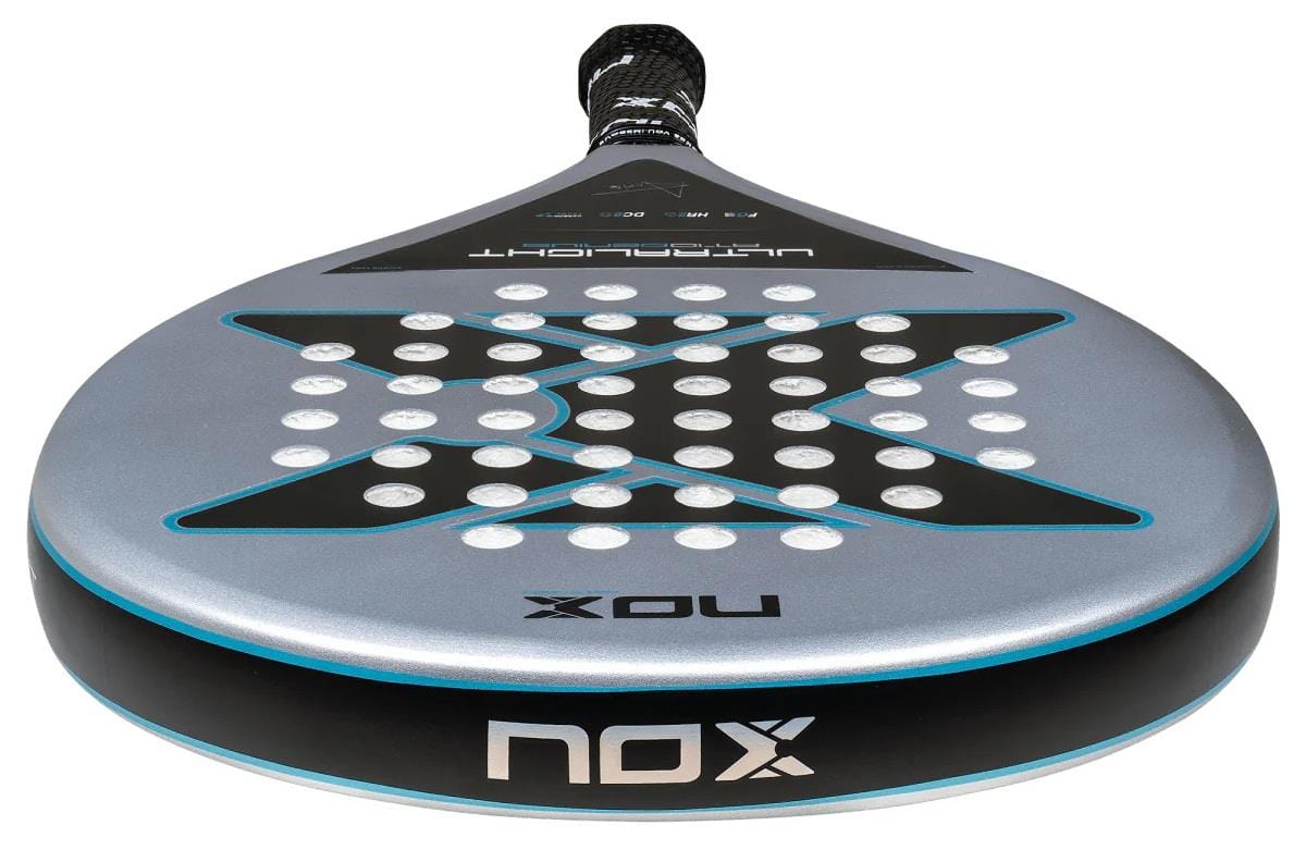 A close-up of the NOX AT10 Genius Ultralight By Augustin Tapia 2025 padel racket shows its round, dark gray face with a bold “X” design, small holes, “NOX” branding on the frame and handle, and an advanced HR2 core.