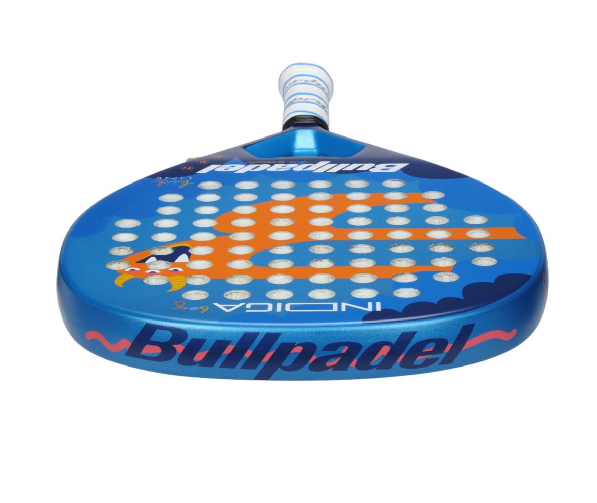 Close-up of a blue Bullpadel Indiga Junior 25 Boys padel racket featuring orange designs and circular perforations. The word "INDIGA" is visible on the upper side. Enhanced with Grip Zone technology, its white and blue-striped handle ensures optimal control for young players.