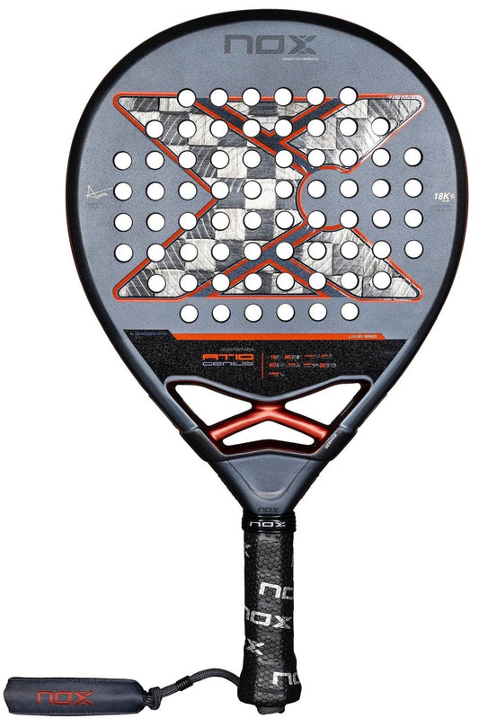 The NOX AT10 Luxury Genius 18K Alum By Agustin Tapia 2025 padel racket features a black and gray design with red and white "X" accents, 18K Alum face, circular holes, branded grip tape, and a black wrist strap.