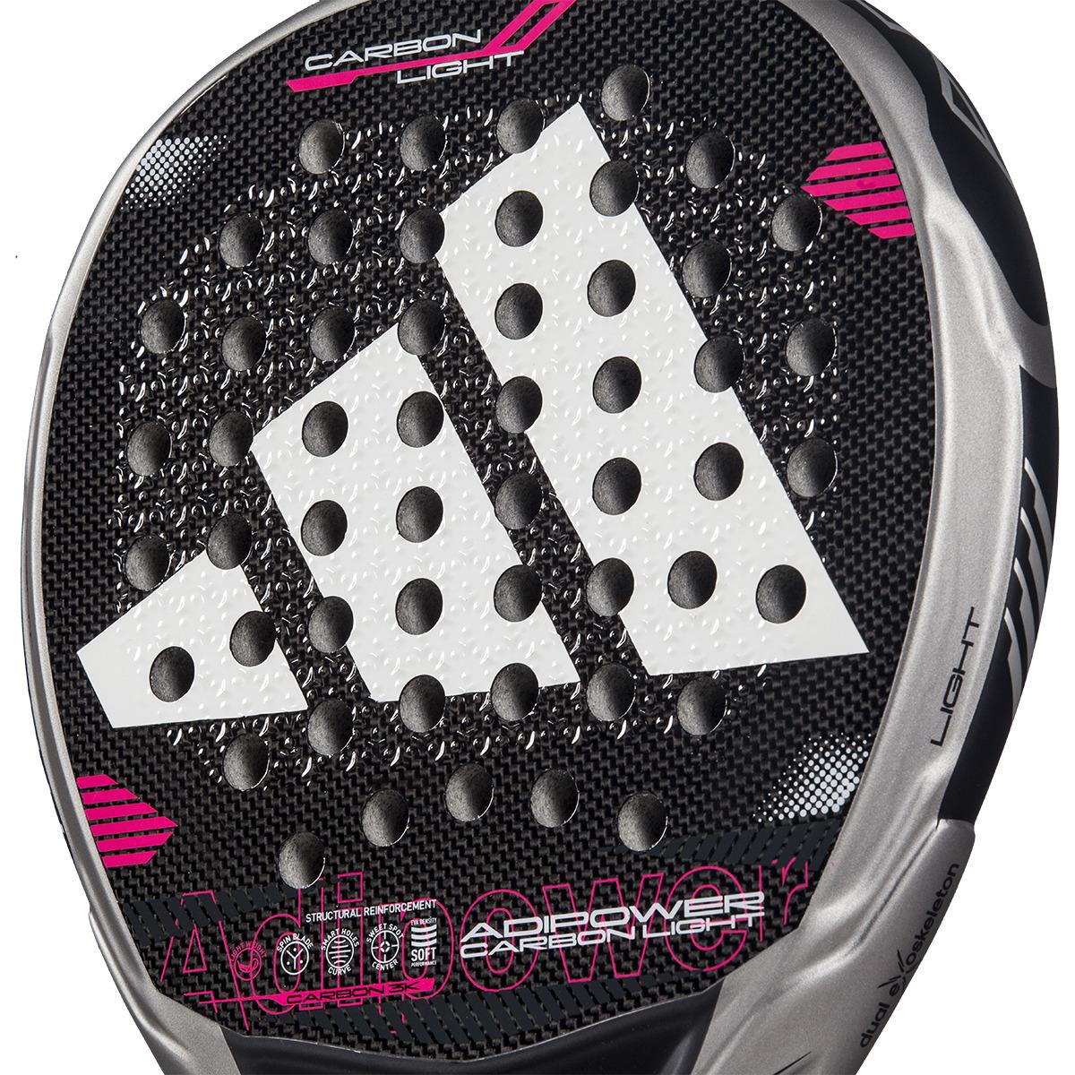 Close-up of the ADIDAS Adipower Carbon Light 3.4 Padel Racket featuring Carbon 3K Fibre and a dotted pattern. The logo and branding are in white and pink, with partial "Adipower" text visible. A silver edge is labeled "Carbon Light," showcasing the innovative 3D Spin Blade Mold design.