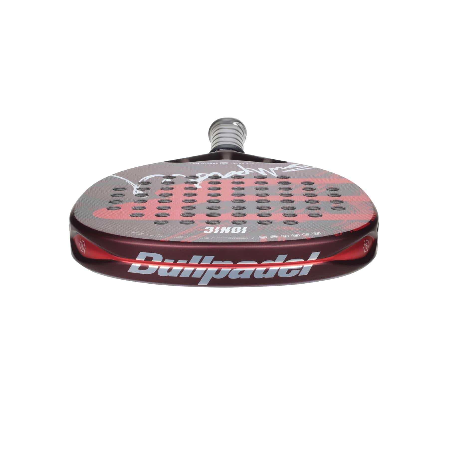 A vertically positioned Bullpadel Ionic Power 2024 Padel Racket in black and red features a Diamond Head Shape and a perforated surface. The "Bullpadel" brand name is visible on the side, and its handle is wrapped with a gray grip for comfort.