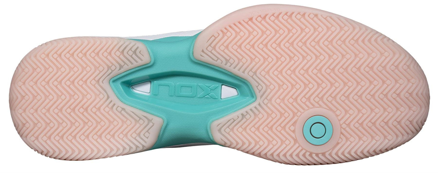 The image shows the sole of the NOX AT10 Lux Women's Padel Shoes in White/Potpurri. Designed by NOX, it features a herringbone pattern and "NOX" embossed at the center, offering excellent traction for power play on the padel court.