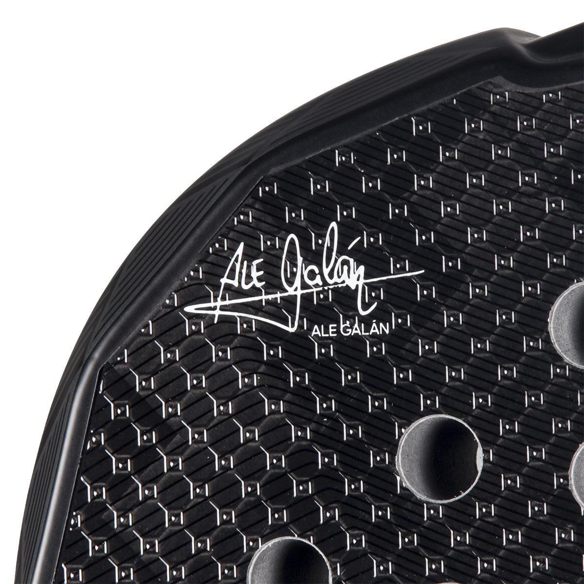 Close-up of the adidas Metalbone 3.4 Padel Racket - Black/White designed for advanced players, featuring a textured surface with hexagonal patterns and circular holes. The "Ale Galán" signature is prominently displayed, adding finesse to this precision-engineered masterpiece.