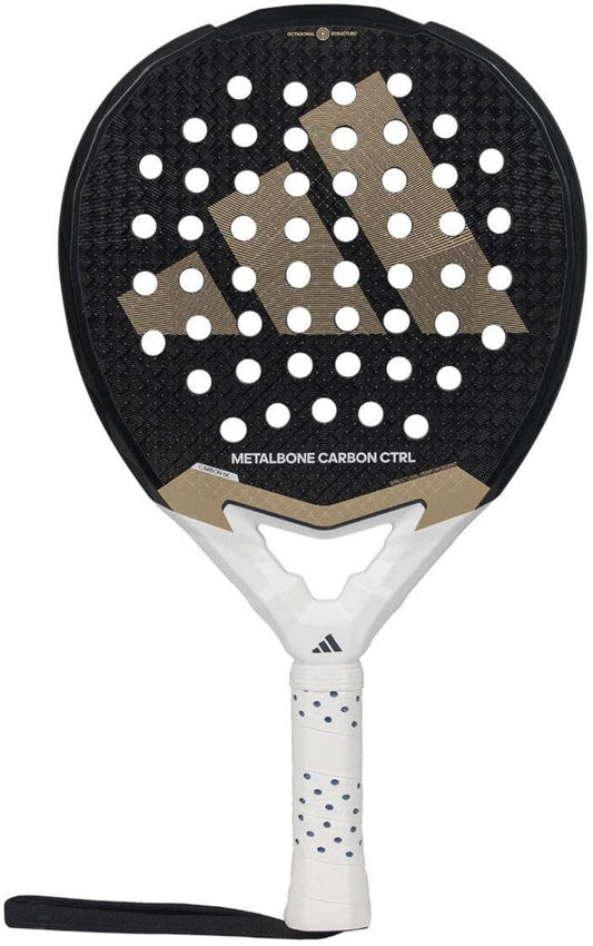 The ADIDAS Metalbone Carbon CTRL 3.4 padel racket for advanced players features a perforated black surface with a gold geometric logo, a white handle with black polka dots, and includes a wrist strap.