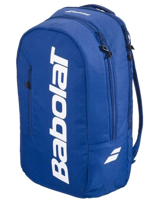 The Babolat Court Lite Padel Backpack in dark blue features white logo lettering and two zippered compartments, including a dedicated racket space. Shown angled on a plain background.