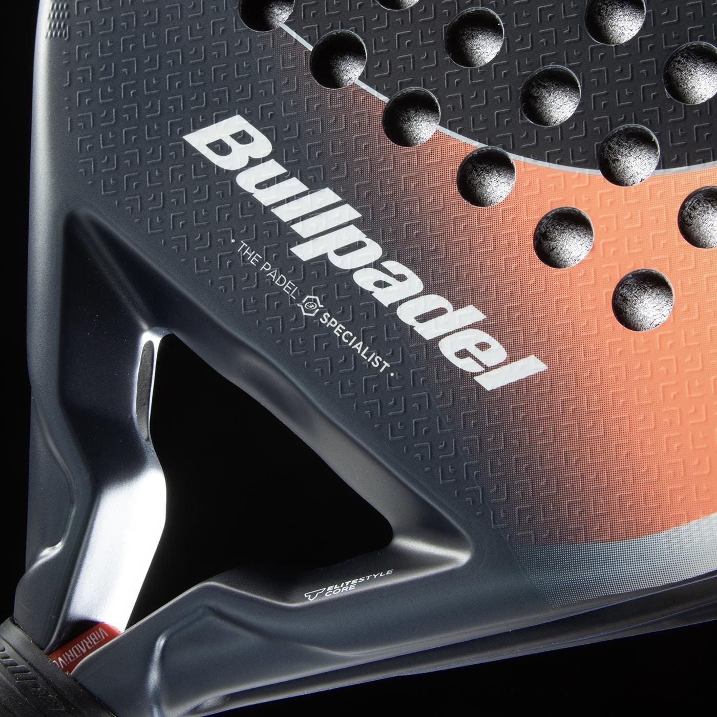 Close-up of the Bullpadel Elite W 2026 Padel Racket in black and white, displaying its textured surface with round holes for top-level performance. “THE PADEL SPECIALIST” appears below the main Bullpadel logo.