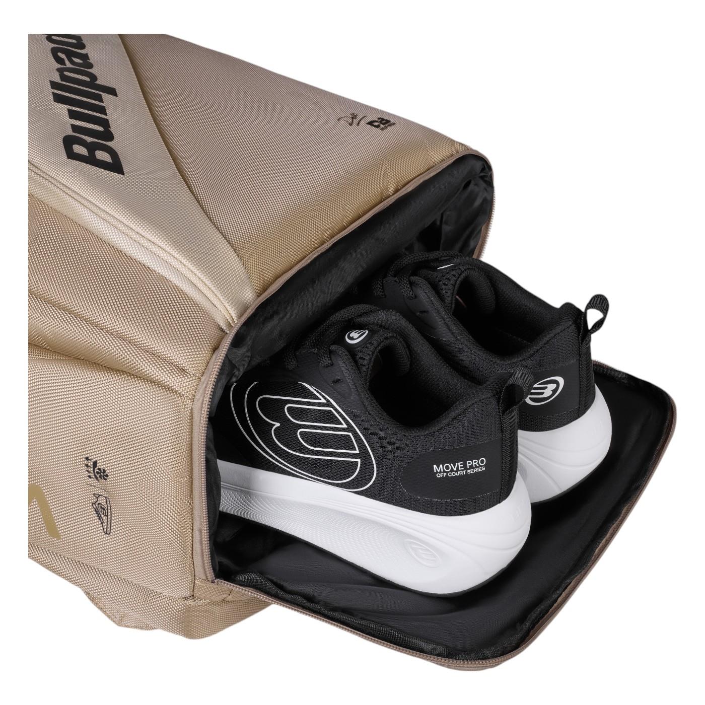 A beige Bullpadel Vertex 25 Padel Backpack - Stone, with a reinforced thermo-lined compartment, holds a pair of black and white athletic shoes. Perfect for carrying your Vertex Padel Racket, it features a side zip and logo.