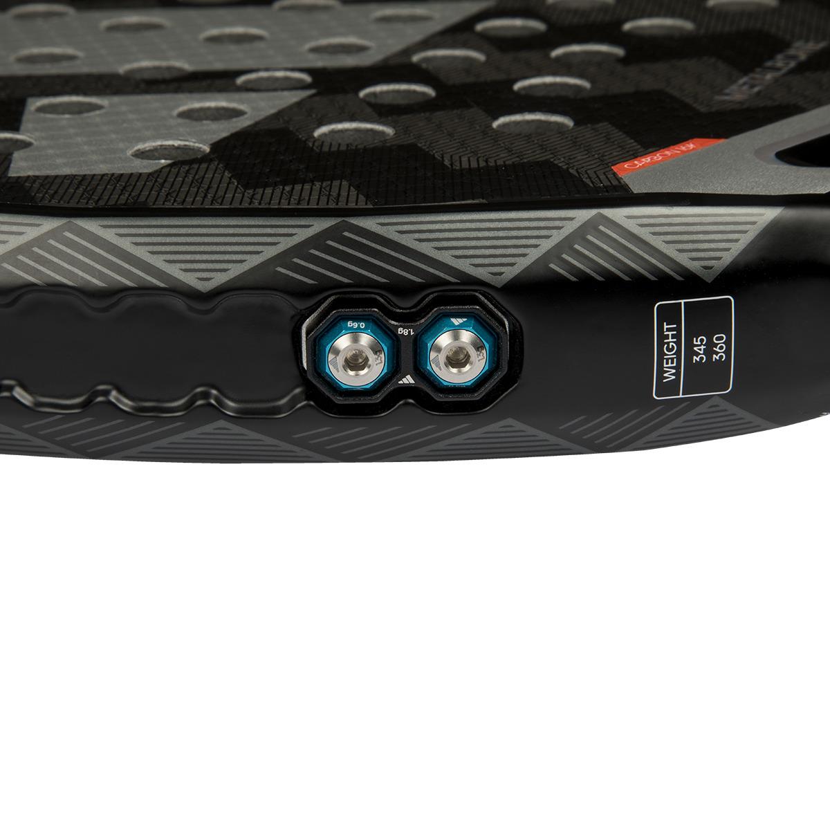 Close-up of a paddleboard's black matte surface, featuring textured patterns and two metallic blue valve connections, mirroring the detail of an adidas Metalbone 3.4 padel racket in black/white. The board's weight specifications are displayed nearby.