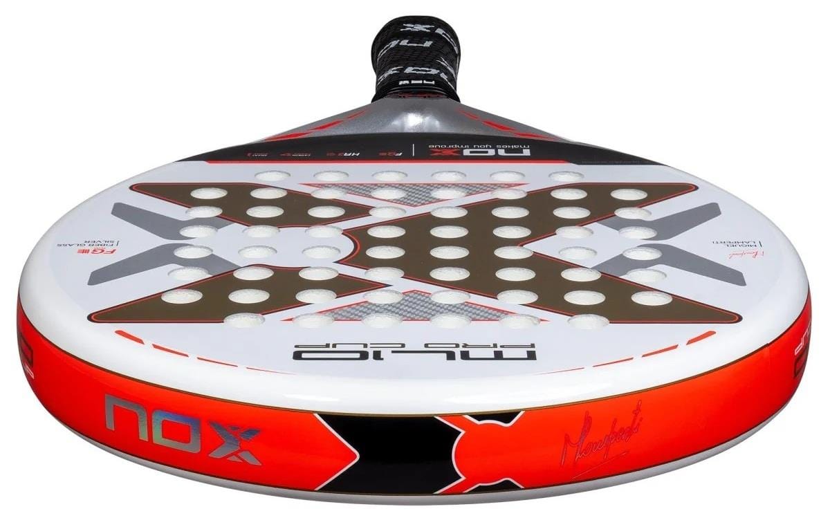 A close-up of the NOX ML10 Pro Cup Coorp By Miguel Lamperti 2025 padel racket shows its red, black, and white colors with a bold "X" design and multiple holes for better aerodynamics, inspired by pro player Miguel Lamperti.