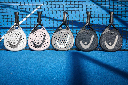 Five HEAD Speed Motion 2025 padel rackets, featuring Power Foam and Auxetic 2.0 technology, are lined up against a net on a blue court. The copper/black rackets have perforated faces and distinct patterns, with varying handle grips that range from neutral to black in color.