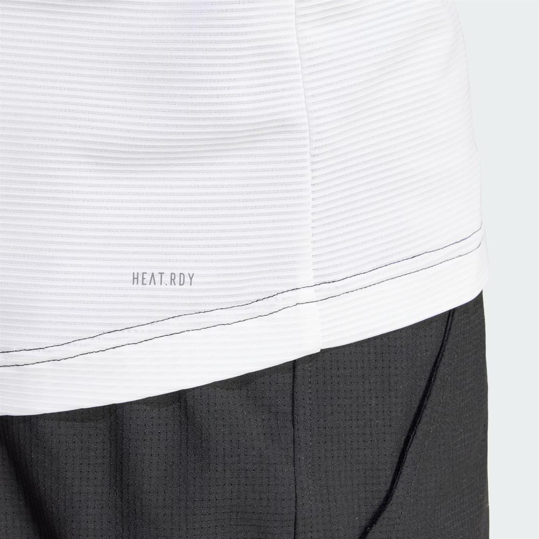 Detailed view of the adidas Men's Pro Freelift 3D Padel T-Shirt in Black/White, showcasing a white textured fabric with delicate vertical lines and "HEAT.RDY" text. Below, the black material features a grid-like pattern. A visible black seam joins these fabrics, contributing to the shirt's sleek design by adidas.