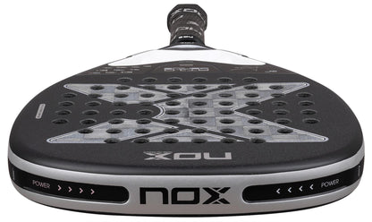 Close-up of the NOX Luxury AT10 Genius Attack 18K Alum By Agustin Tapia 2026 Padel Racket, featuring a black and silver face with a large "X" design, circular perforations, and an 18K aluminised carbon finish.