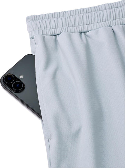 A black smartphone peeks from the side pocket of Yonex 15241EX Knit Men's Padel Shorts in Silver Grey, highlighting the sleek design and functionality of these performance shorts by Yonex.