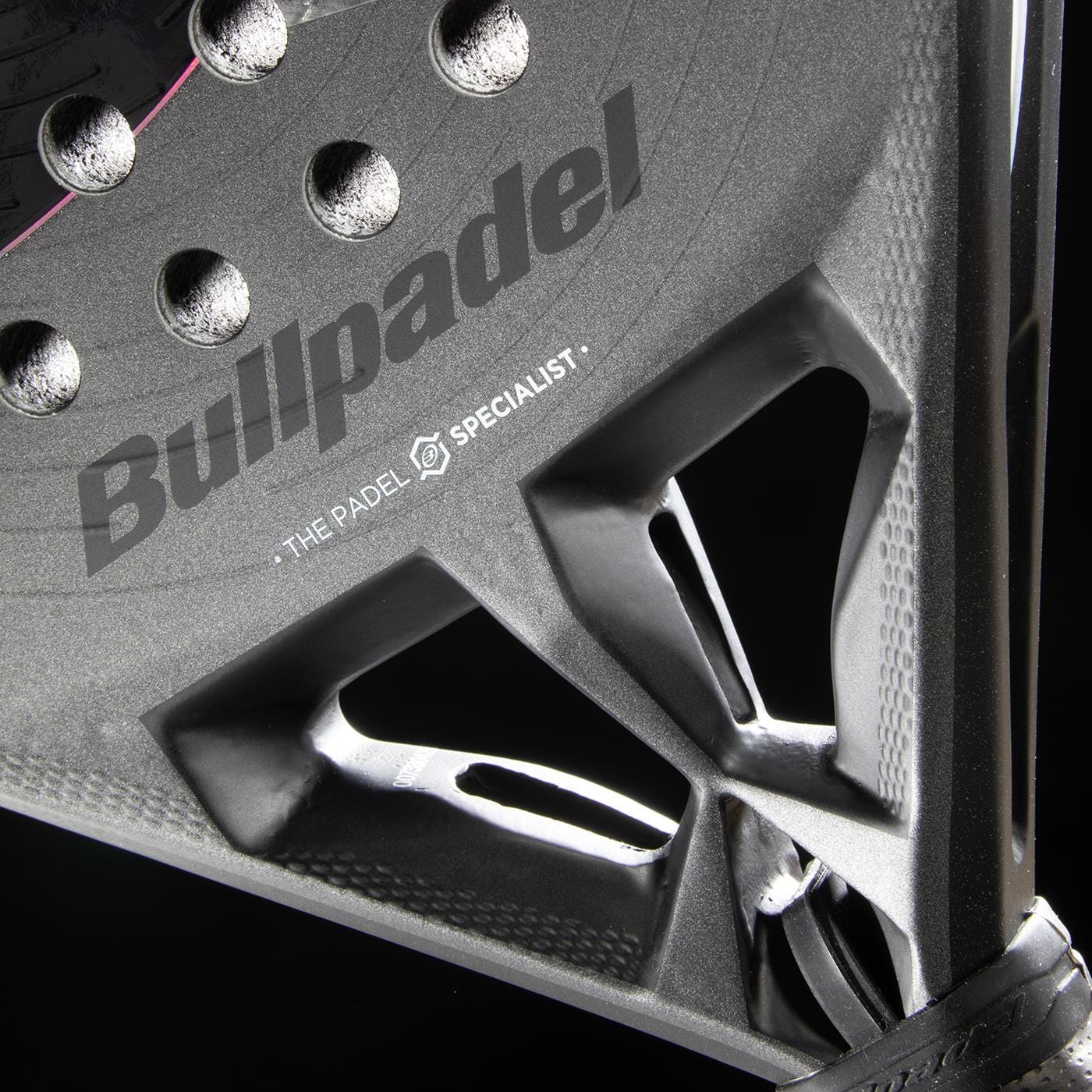 Close-up of the Bullpadel HACK 04 Hybrid 2026 Padel Racket in grey/black, featuring the Bullpadel logo and structural holes, highlights its dynamic power, detailed texture, and design on a dark background.