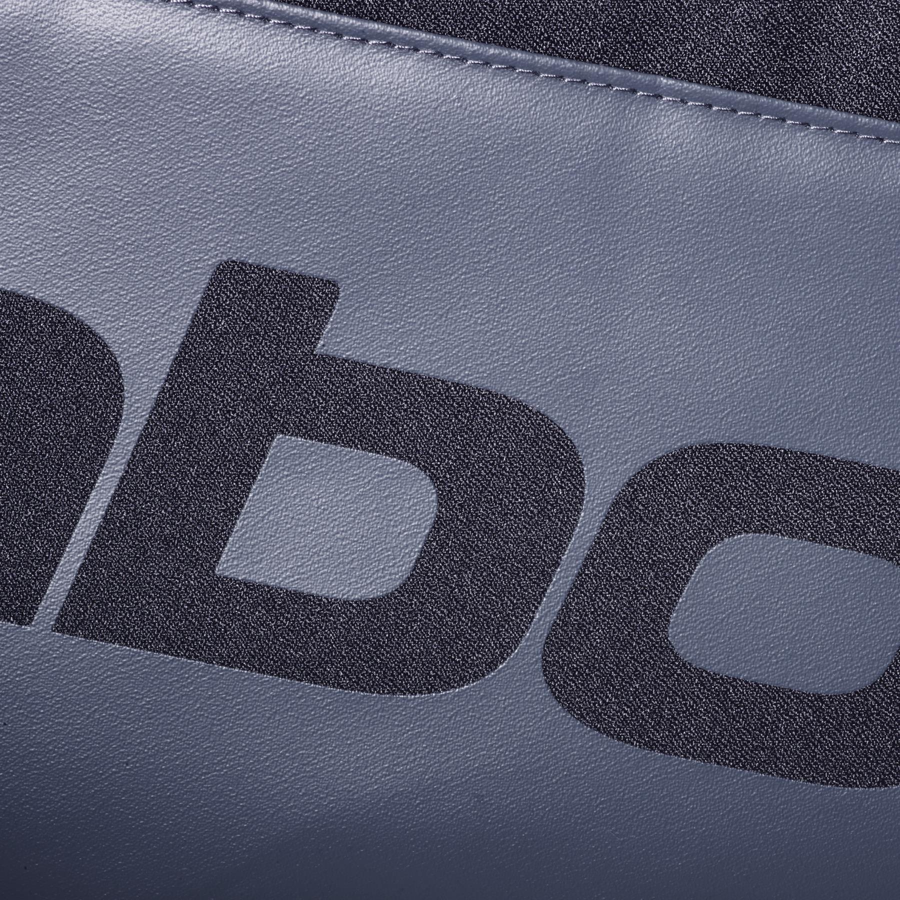 Close-up of textured gray material from the Babolat Court S Padel Racket Bag - Black, featuring a bold black lowercase "b"—showing only part of the text on this Babolat padel equipment.