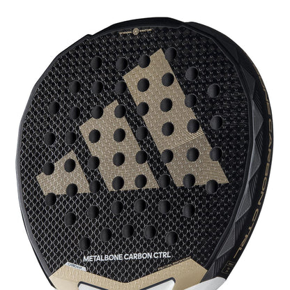 The adidas Metalbone Carbon CTRL 3.4 Padel Racket in black and gold features a sleek pattern with circular indentations, ideal for advanced players. "Metalbone Carbon CTRL" is elegantly printed on the lower part of the racket.