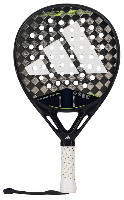 The ADIDAS Cross It CTRL 3.4 Padel Racket, designed for advanced players, features a textured surface with black and grey diagonal stripes. Its Carbon 15K composition enhances precision, while the handle offers a secure white grip with small black dots and an attached black wrist strap.