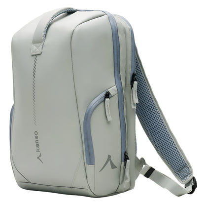 The Kanso Intuko Padel 23L Backpack in Grey boasts a sleek design with multiple zippered compartments, a racket compartment, and an adjustable padded strap. Featuring the brand's reflective logo on the side, this backpack stands upright on a neutral background.