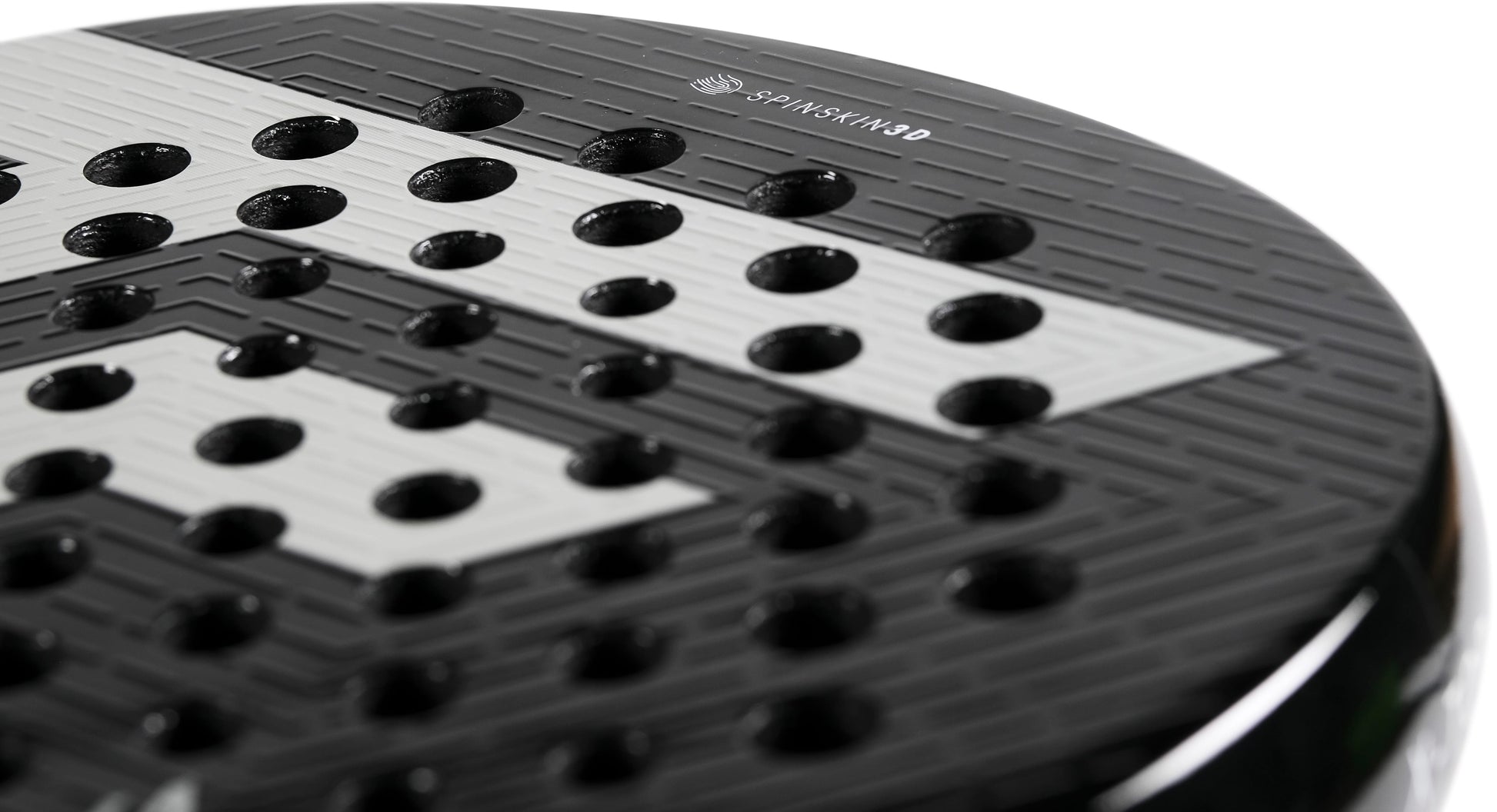Close-up of a black and white perforated surface, likely the face of a Tecnifibre Curva Power 2026 Padel Racket crafted from 18K carbon, featuring a geometric pattern and the “Tecnifibre” brand name visible at the top.
