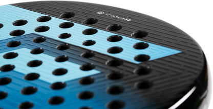 Close-up of the Tecnifibre Curva Soft 2026 Padel Racket, a black and blue perforated racket with a textured surface featuring circular holes and the word “SPINSHOT” printed near the top edge. Its distinctive teardrop head shape exemplifies Tecnifibre’s advanced design.