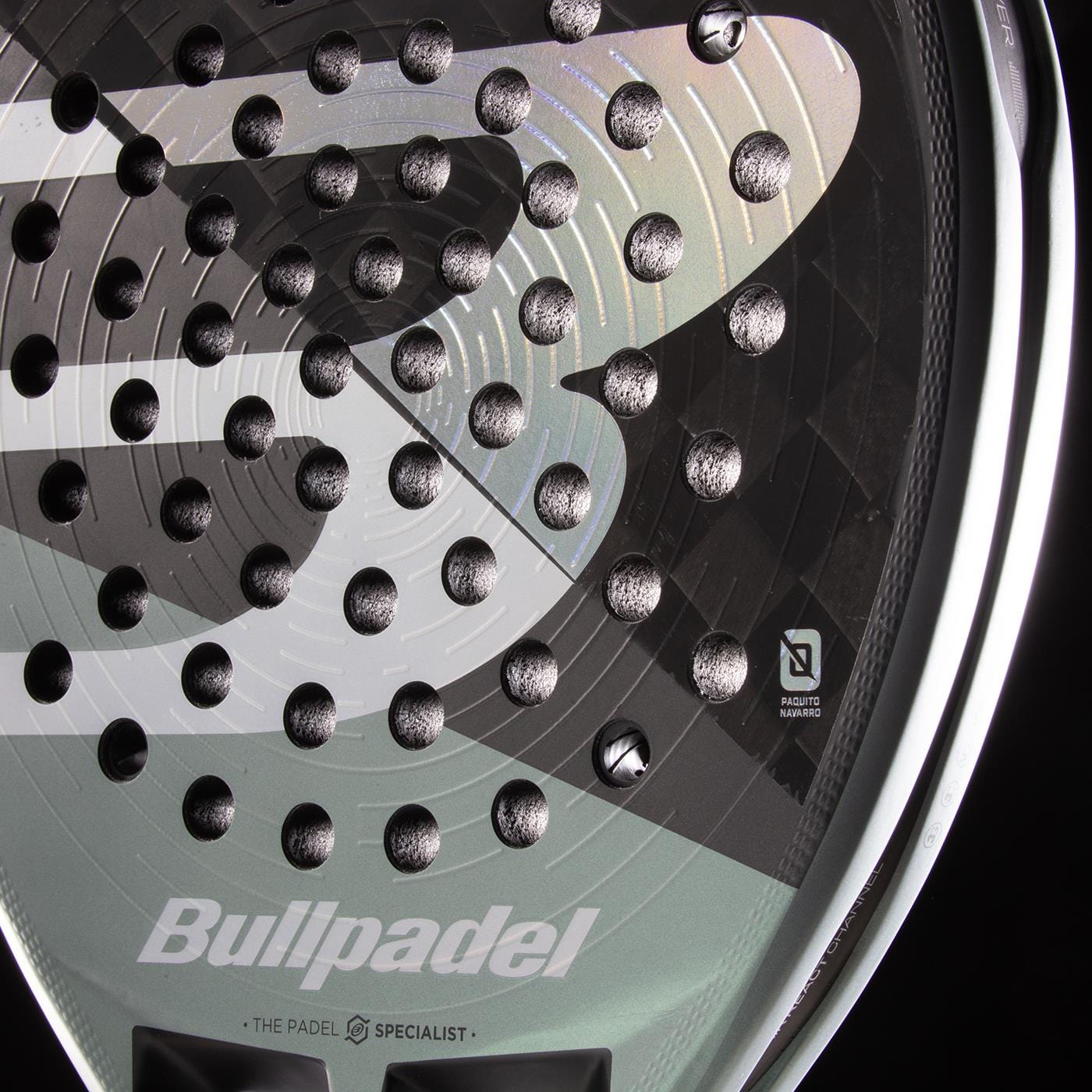 Close-up of the Bullpadel HACK 04 2026 Padel Racket in Black/Grey, highlighting its textured face with round indentations and bold Bullpadel logo. Sharp lighting accentuates its dynamic power and refined design.