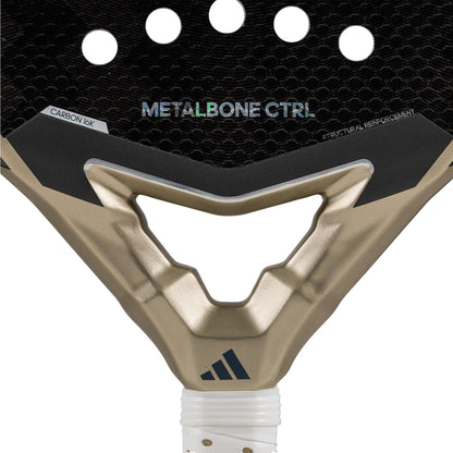 A close-up of the adidas Metalbone CTRL 3.4 Padel Racket - Gold displays its black surface with circular cutouts and metallic gold accents, highlighting "METALBONE CTRL 3.4" and "CARBON 16K" text. The octagonal structure enhances stability, with the adidas logo prominently visible at the bottom.
