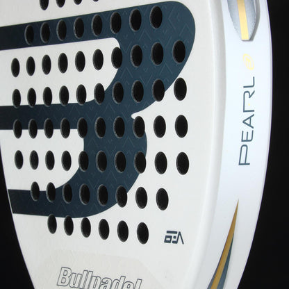 Close-up of the lightweight Bullpadel Pearl 2026 Padel Racket - White by Bullpadel, featuring black circular holes, gold accents, and "PEARL" logo—designed for injury prevention—set against a black background.