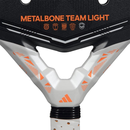 Close-up of the adidas Metalbone Team Light 2026 Padel Racket in black, featuring "METALBONE TEAM LIGHT" in orange. The handle showcases white and orange geometric patterns with the adidas logo—designed for advanced players.